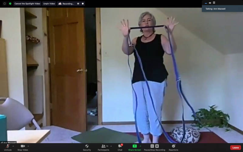 middle-aged woman teaching yoga through a zoom class