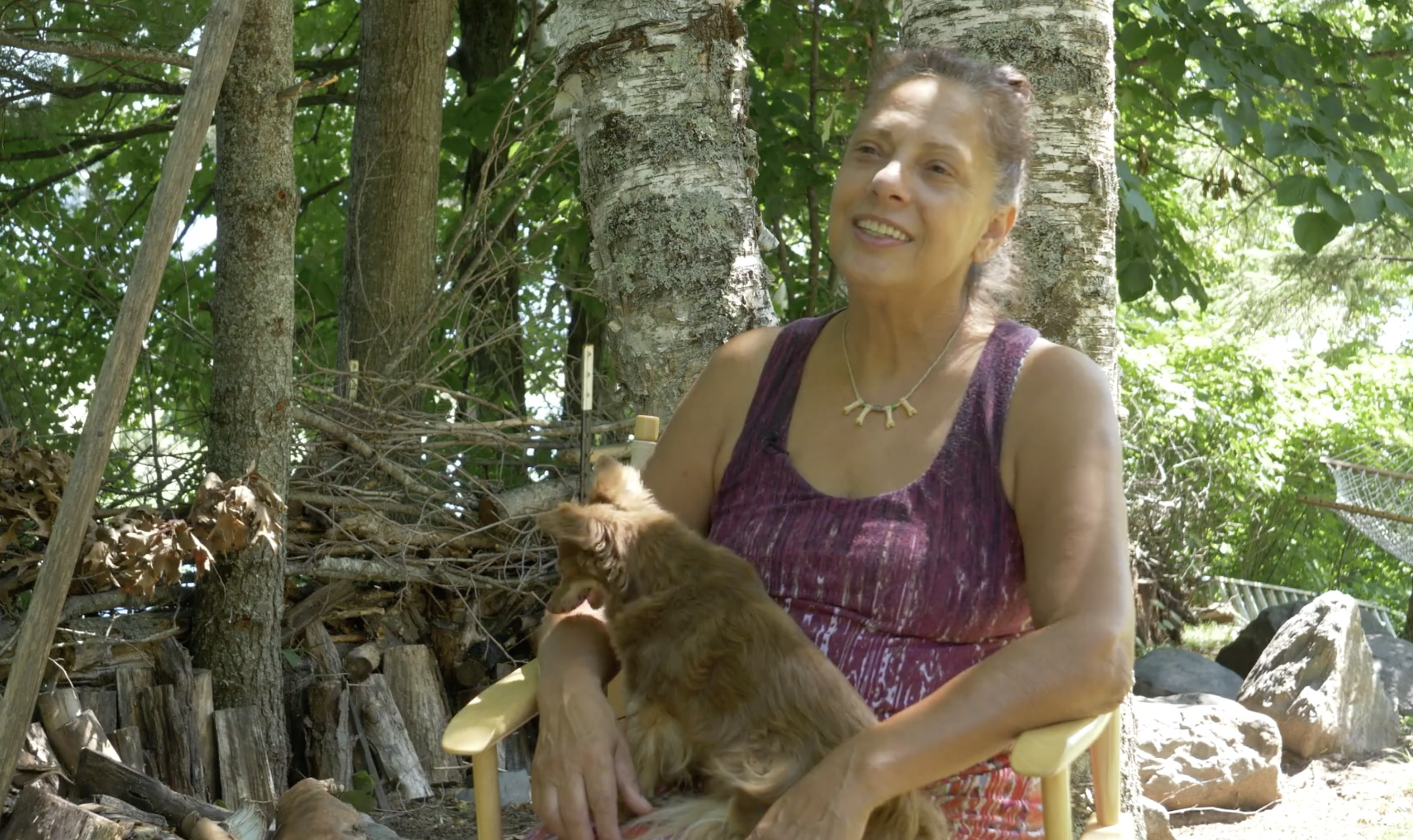 Photo of the artist Karen Savage Blue sitting outside in the woods holding her little dog