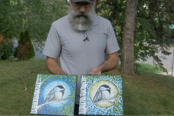 Aaron Kloss holding paintings of chickadees