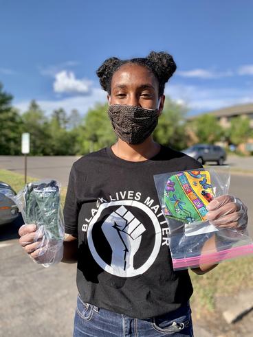 Young woman holding two plastic bags with masks and wearing a black lives matter t-shirt